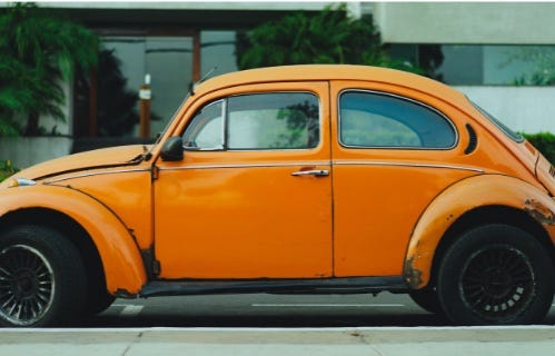 An older model orange Volkswagen beetle.