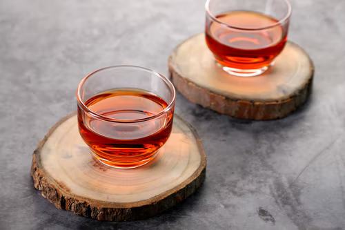 Two transparent cups with reddish-orange fluid in it.