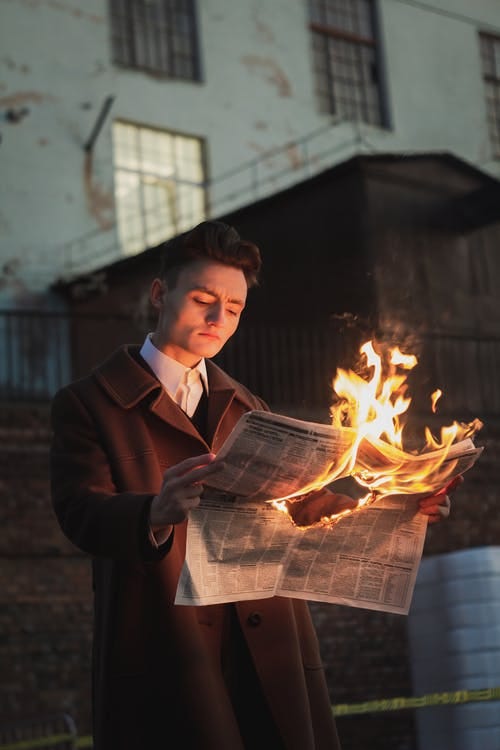Someone reading a newspaper that’s on fire.