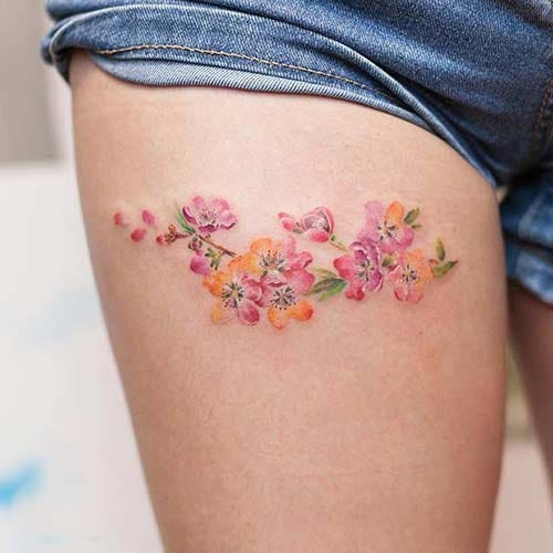 woman thigh colorful flowers tattoo