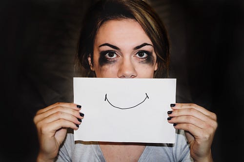 battered woman with a smile on a piece of paper drawn in front of her face