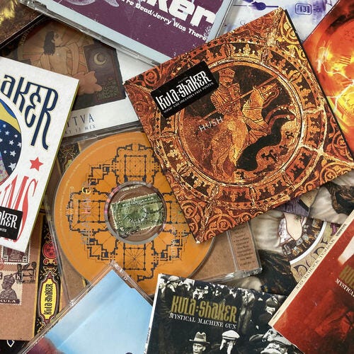 Kula Shaker CDs of singles and B-sides scattered in a pile; “Hush” CD most prominently featured in off-center top right