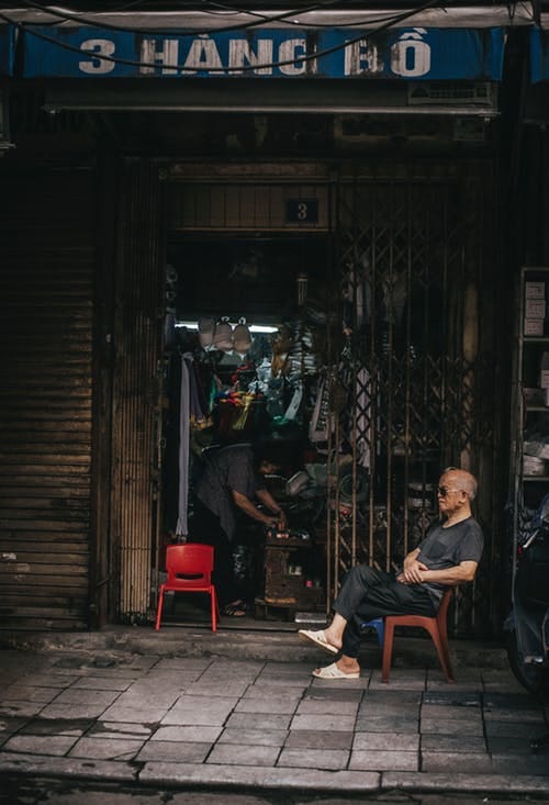 A shop keeper sits outside his ramshackle store in SouthEast Asia
