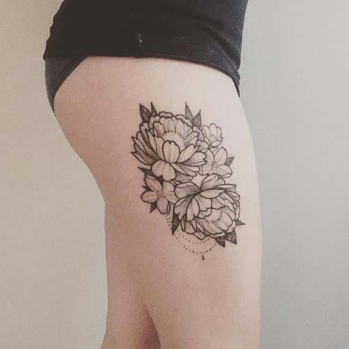 woman thigh side flower tattoo