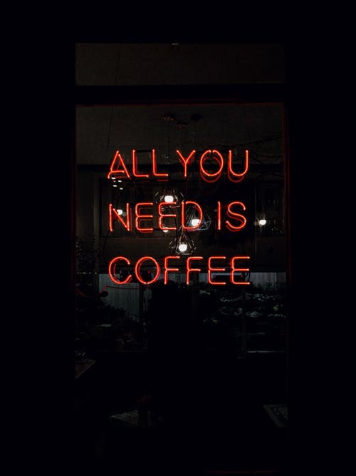 Red neon sign saying “all you need is coffee”