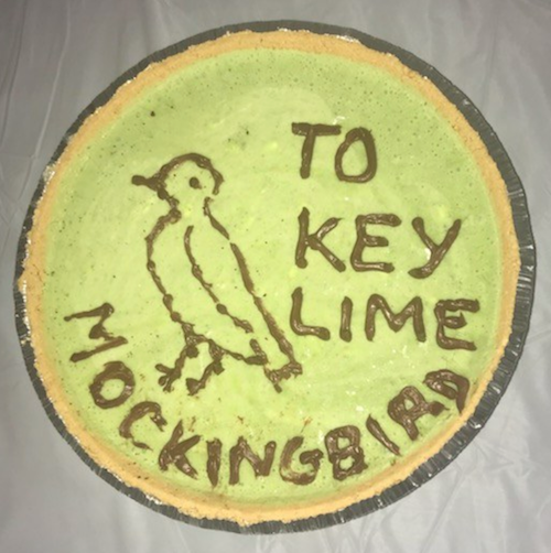 a key lime pie with a picture of a bird on it and the writing “To Key Lime Mockingbird”