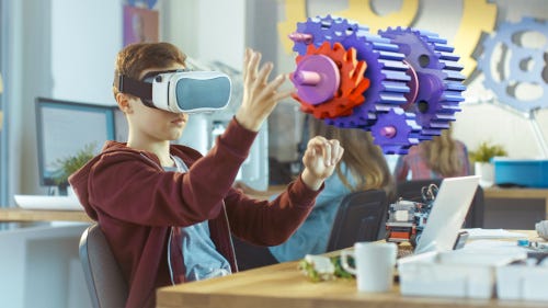 Student in VR headset sits at desk in detailed virtual classroom, raising hand next to a floating 3D model.