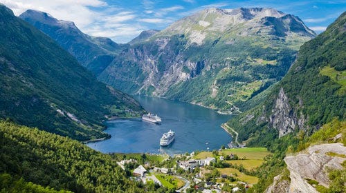 Imagem linda de uma paisagem na Escandinávia, um vale com um lago no centro com dois navios de cruzeiro.