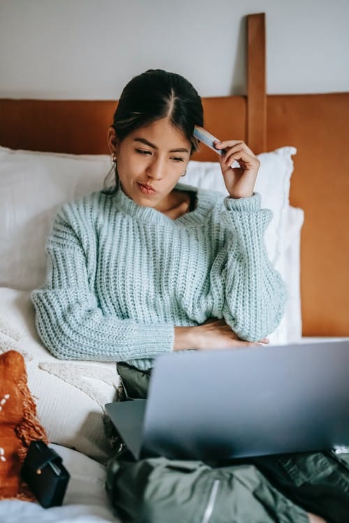 Girl in bed confused looking at her laptop
