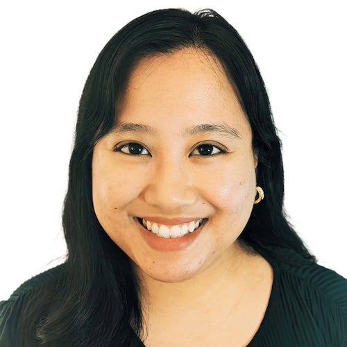 Jia, a smiling Filipino woman with shoulder-length black hair and brown eyes. She is wearing a dark green top and gold hoops.