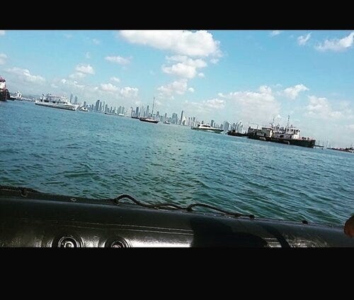 a photo taken from the perspective of inside a black boat that is sitting on the navy blue water outside of Panama City, Panama