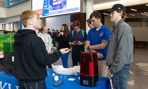 A student shows his 3-D printed figurines to onlookers.