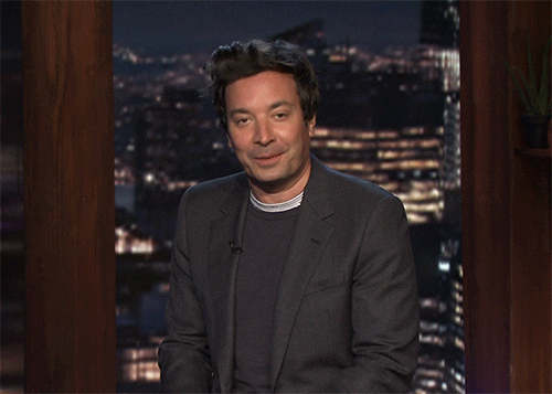 GIF of Jimmy Fallon pretending to write and smiling secretively.