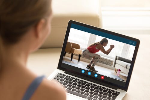 Woman watching a workout on a laptop screen