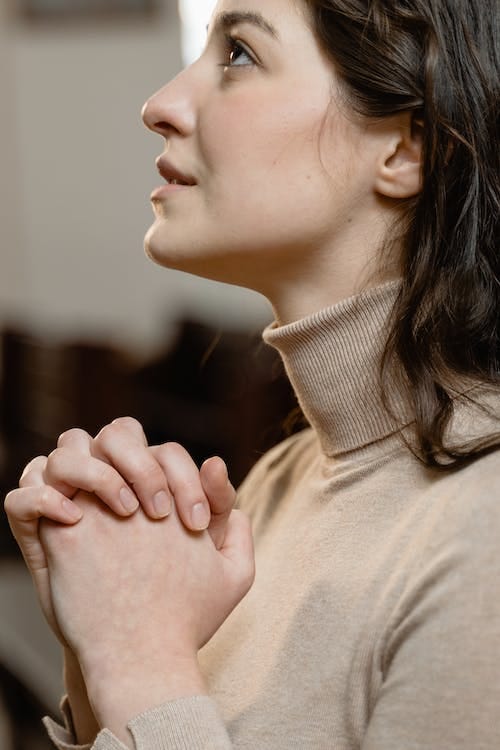 a woman praying to God in the church with folded hands