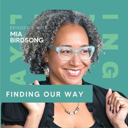 Photograph of Mia Birdsong, wearing blue reading glasses and smiling, raising their hands shoulder level in fists as in excitement. Photo is transposed on a teal background, with the podcast title FINDING OUR WAY overlaid in white font.
