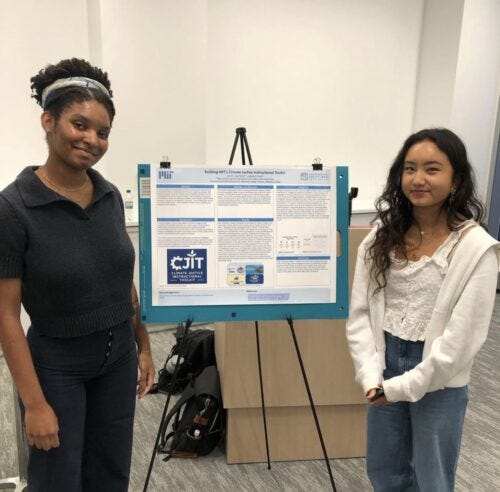 Photo of two college-aged students standing in front of an easel holding an informational poster board
