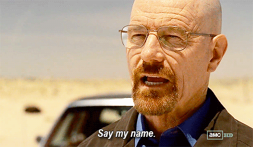 O gif animado mostra Walter White, protagonista de Breaking Bad. Um homem de meia idade branco, careca, com um óculos e um cavanhanque, falando as palavras: “Say my Name”. Ele está de frente para um carro, em um deserto.