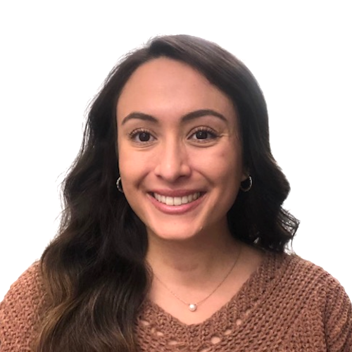 Headshot of Yazmin, a young light-skinned Mexican-American woman. She is looking at the camera with an open-lipped smile. She has long, wavy light brown hair and is wearing a caramel top with a pearl necklace.