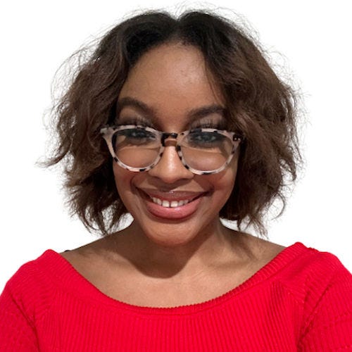 Photo of Ariel, a Black woman, from shoulders up. She is looking at the camera with a full smile. She is wearing a red dress. Her hair is dark brown with flat-ironed curls.