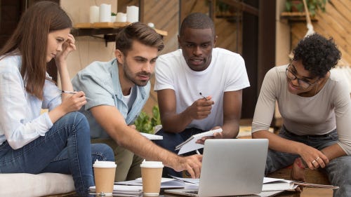 Diverse group of friends talking, using a computer, doing research