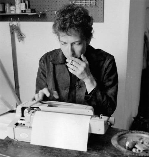 Bob Dylan at the typewriter smoking.