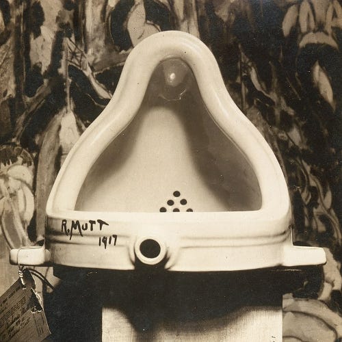 Photo of Duchamp’s 1917 work of at called “Fountain”. The work is an urina on a pedestal and signed by Duchamp as “R. Mutt”.