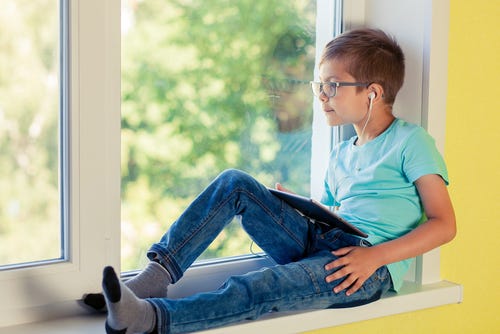 Boy sitting listening to and reading a book on the Kindle app