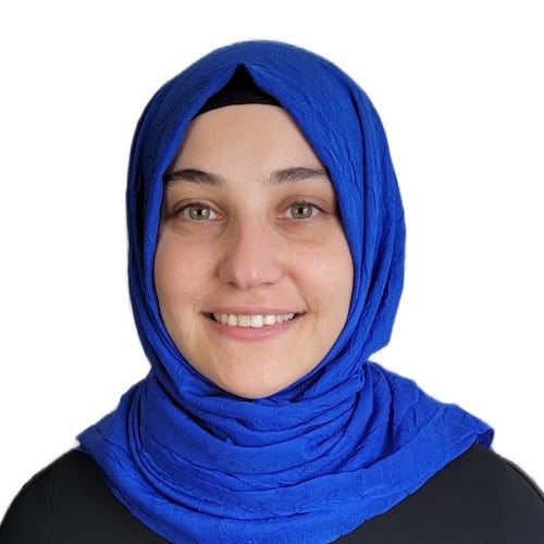 Photo of Beyza from the shoulders up. She is looking at the camera with an open-lipped smile and a close-lipped smile. She is wearing a black shirt and a sax blue headscarf.