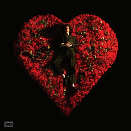 Conan Gray lying in a bed of roses and rose petals shaped into a heart. The cover of Conan Gray’s Super-ache album.