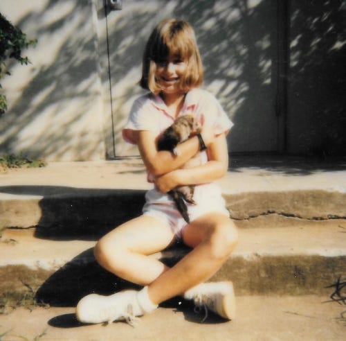 The author sits on steps hugging a ferret to her chest.