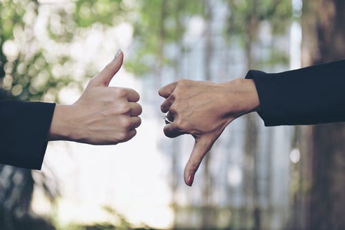 Image of two hands, one with the thumb up, one with the thumb down