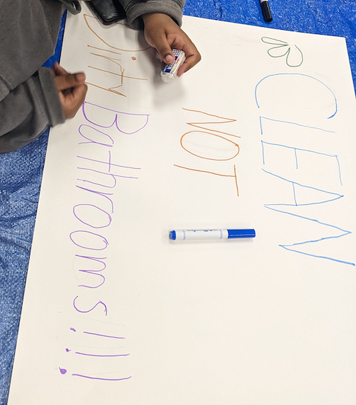 Photo of a student making a sign: “CLEAN NOT Dirty Bathrooms!!!”