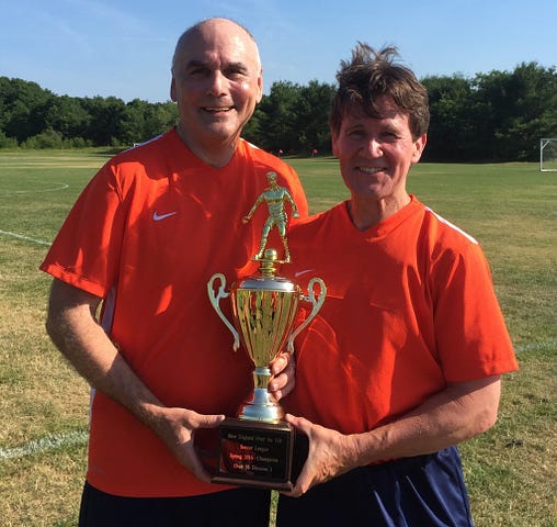 Left to right, Paul Harrison and Brian O’Connor holding the championship trophy for the Over-56 Division of the New England Over the Hill Soccer League tournament. They defeated the Northshore Seadogs, 4-0, in the June 26 final held in Medfield, Mass.