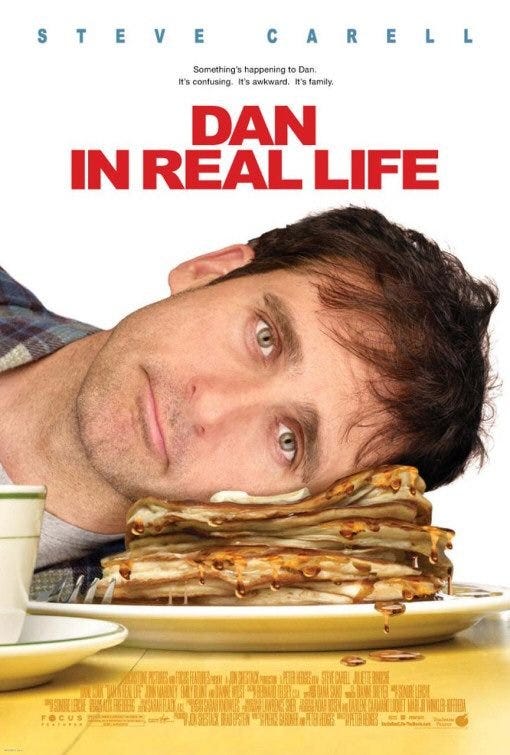 Poster art for the film Dan in Real Life. Steve Carell with dead eyes and 5 o’clock shadow evidently photoshopped to appear as if he has his head passively pressed down on a pile of buttery, syrupy pancakes.