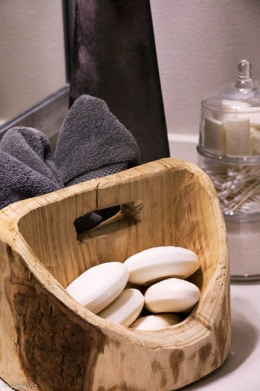 Wooden bath soap holder with white soaps inside.