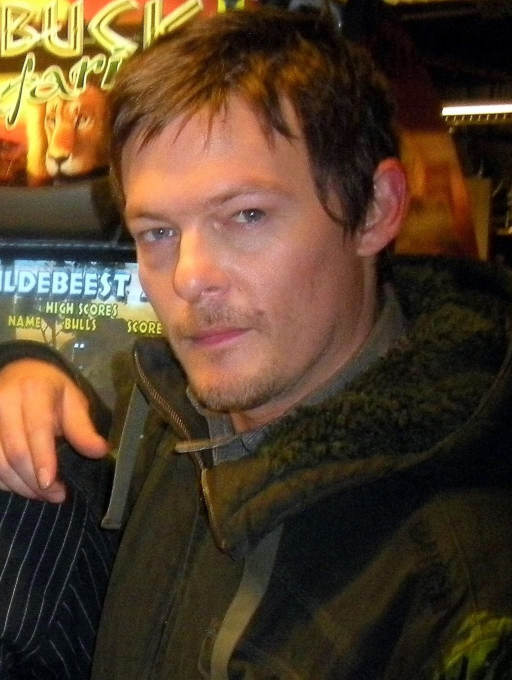 Actor Norman Reedus dressed as his character Daryl Dixon, wearing a sort of heavy brownish poncho.