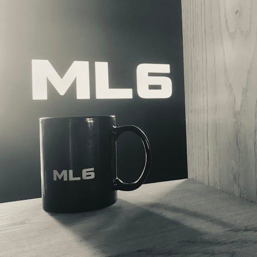 A photo of an actual mug with the font “ML6”. The mug is placed on a shelf with fancy lighting.