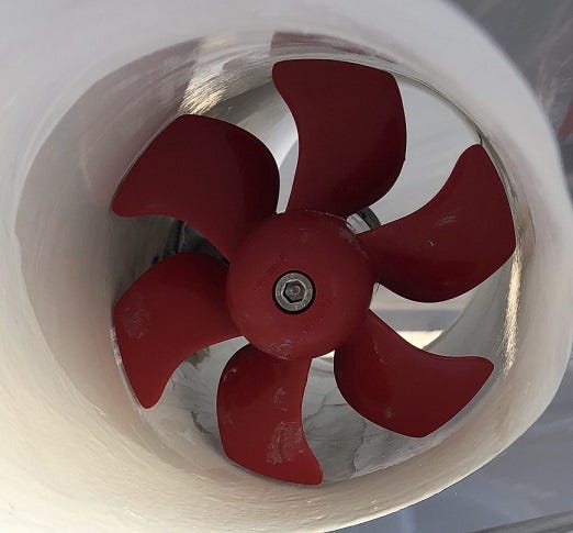 A red 6 bladed bow thruster propeller inside a white tunnel