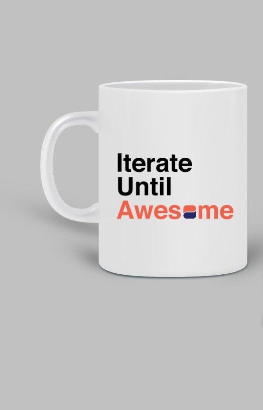 A white cup with the lettering “Iterate until Awesome”