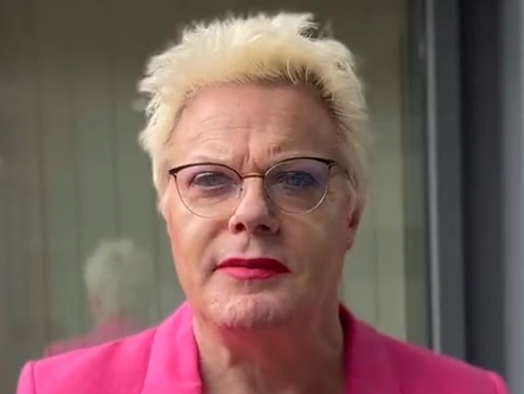 Eddie Izzard (a genderfluid person with short blonde hair and glasses wearing a pink blazer)