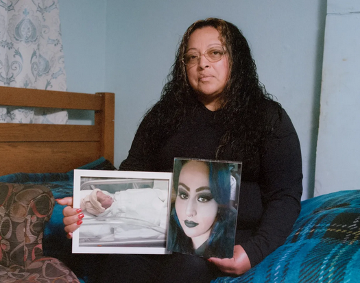 A woman with long hair wearing glasses and a sad expression, holding two photographs.