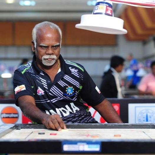 Maria Irudayam sitting in front of the carrom board is about to make his move