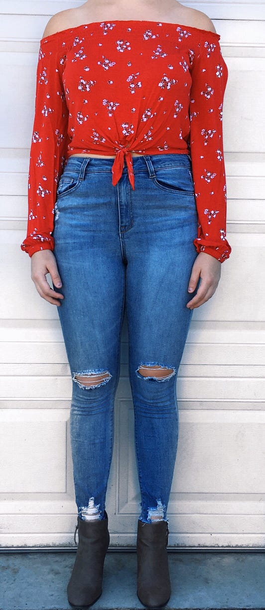 Myself wearing skinny leg high-waisted jeans with rips at the knees and a red shoulder cutoff shirt with white flowers.