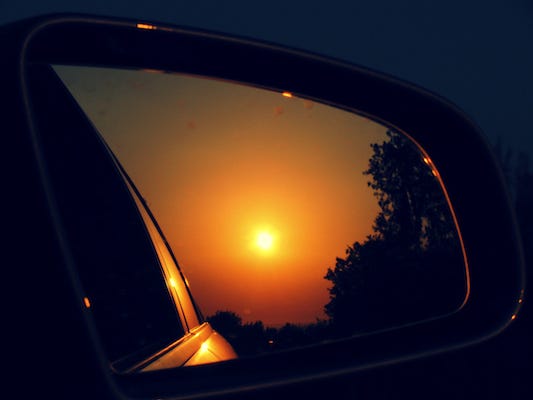A read view mirror on a car showing the sunset
