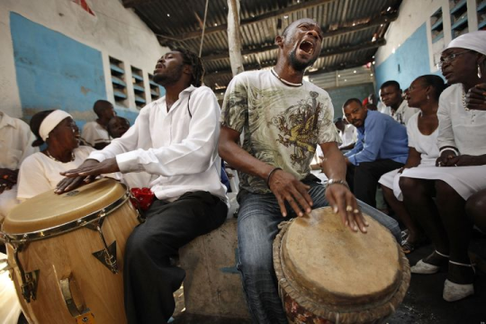 Photo taken from Huffpost: Two Black men beating drums in a Vodou celebration.