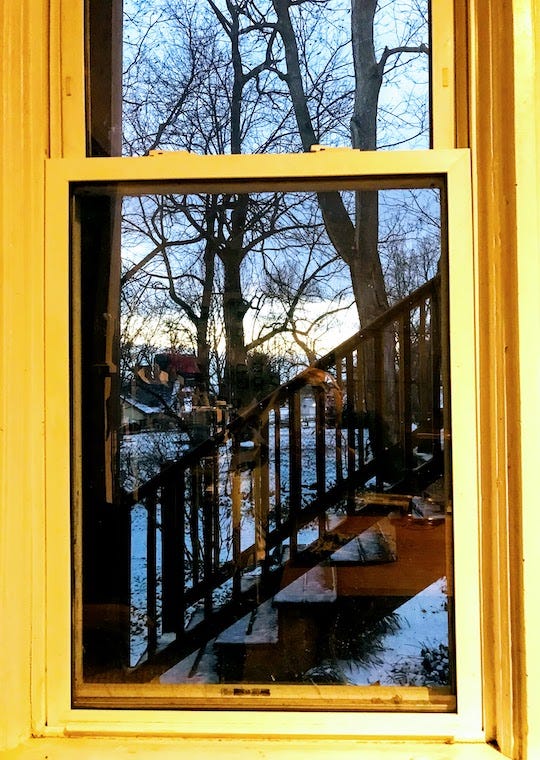 window opening onto late evening scene in winter, wooden stairs, trees in background