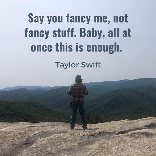 A photo of a man standing in front of a mountain landscape, with a Taylor Swift quote: “Say you fancy me, not fancy stuff. Baby, all at once this is enough.”