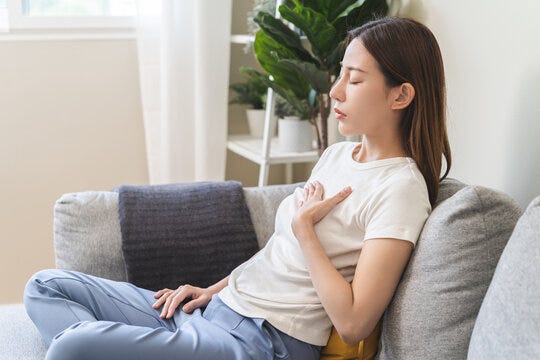 a lady sitting on a couch holding her chest