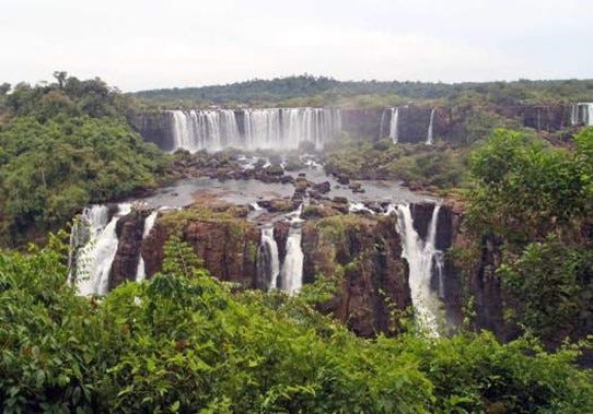 A bird's-eye view of Iguazu Falls featuring two layers of cascading waterfalls amongst lush green jungle